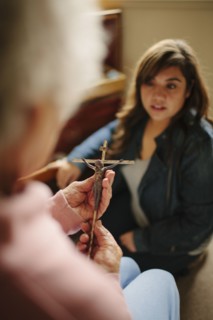 Granddaughter and grandmother praying with crucifix