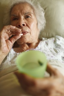 Older mixed race woman taking medication in bed