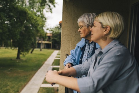 Older woman and granddaughter standing on balcony
