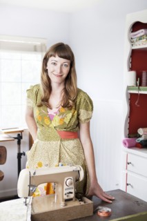 Mixed race dressmaker smiling at sewing table