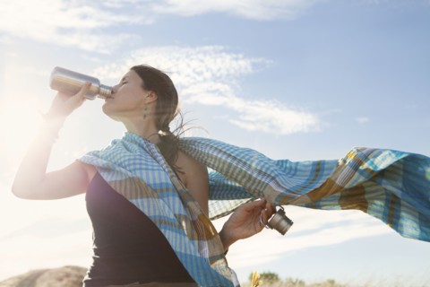 Caucasian woman drinking from bottle in wind
