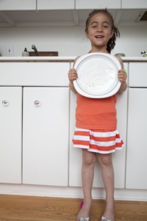 Caucasian girl holding empty plate in kitchen