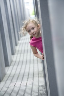 Caucasian girl peeking around corner in hallway