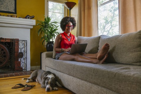 Mixed race woman using laptop on sofa