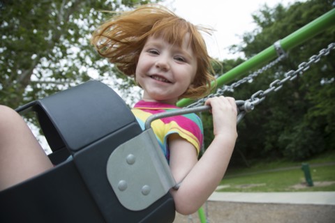 Caucasian girl playing on swing