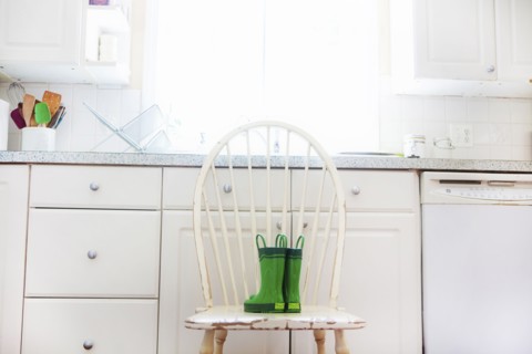 Rain boots of child on chair near kitchen sink
