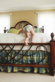 Rear view of baby girl climbing bed