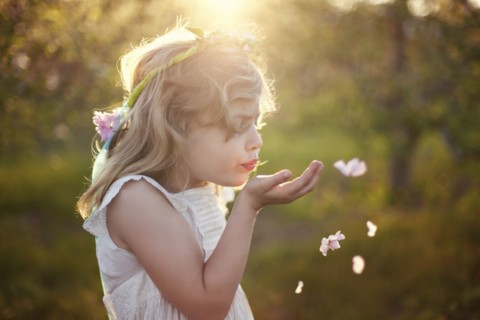 Caucasian girl blowing flower petals outdoors