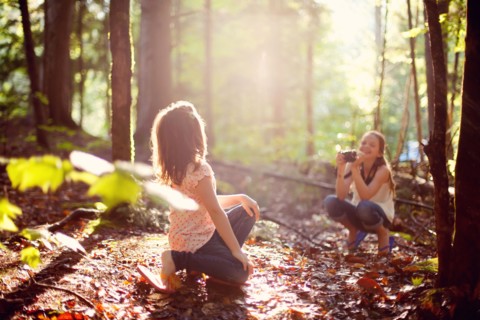 Caucasian girl photographing sister in forest