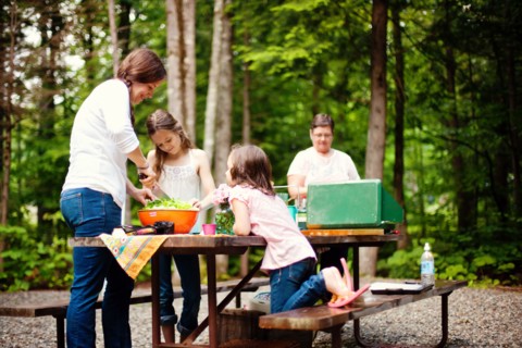 Three generations of Caucasian women cooking at picnic table