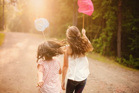 Caucasian girls carrying butterfly nets on dirt road