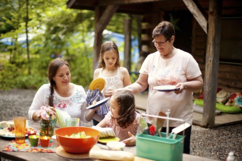 Three generations of Caucasian women cooking outside cabin