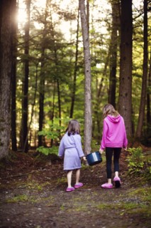 Caucasian girls carrying pot of water in forest