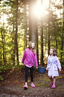 Caucasian girls carrying pot of water in forest