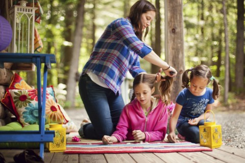 Caucasian mother brushing hair of daughter on porch