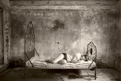 Caucasian woman laying on bed in dilapidated room