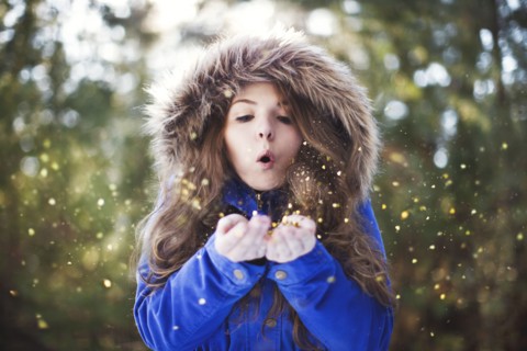 Woman blowing glitter from hands