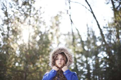 Woman wearing fur hood under trees
