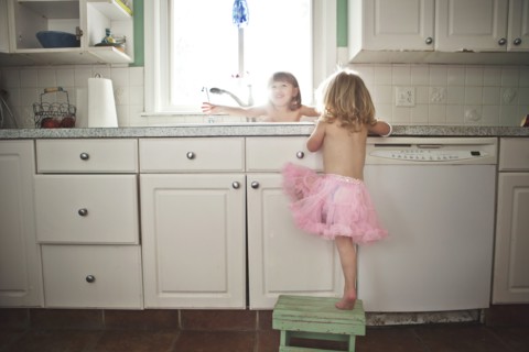 Sisters playing at kitchen sink