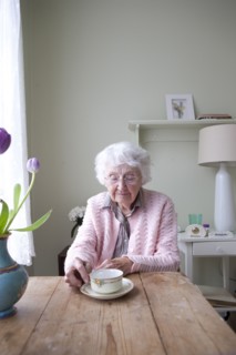 Older woman drinking tea at table