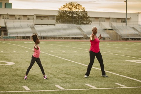 Grandmother and granddaughter exercising on football field