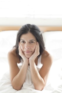 Serious Hispanic woman sitting in bed