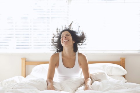 Smiling Hispanic woman sitting in bed