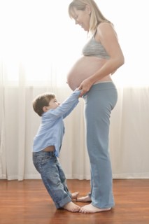 Pregnant Caucasian mother holding hands with son