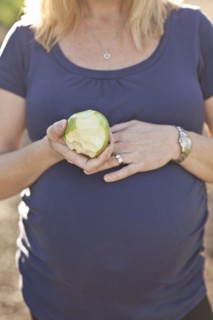 Pregnant Caucasian woman eating apple outdoors