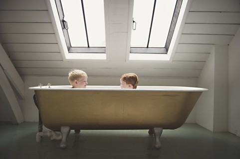 Caucasian brothers sitting in bathtub