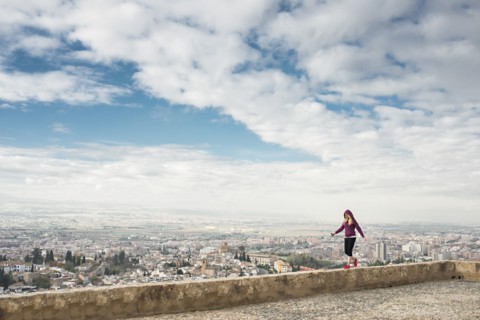 Caucasian woman on wall overlooking scenic view of cityscape