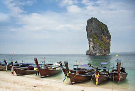 Canoes on sandy beach under cloudy sky