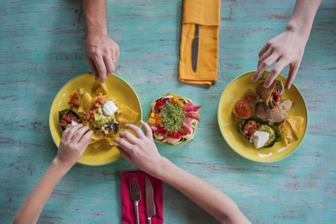 High angle view of hands reaching for food on plates