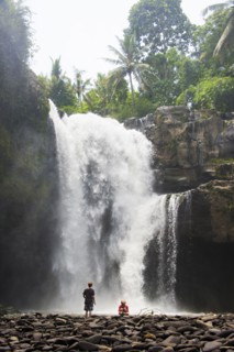 Caucasian tourists admiring waterfall in jungle