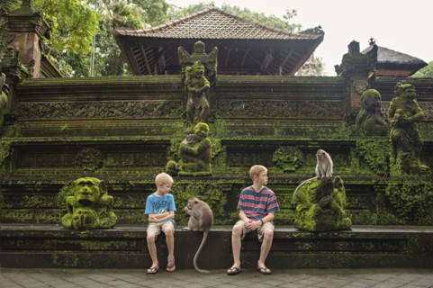 Caucasian brothers examining monkeys on ruins