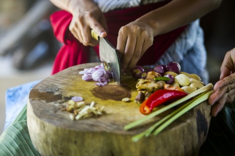 Close up of chefs chopping vegetables on cutting board