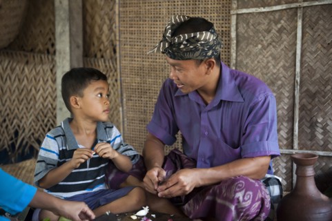 Asian father and son peeling garlic in living room