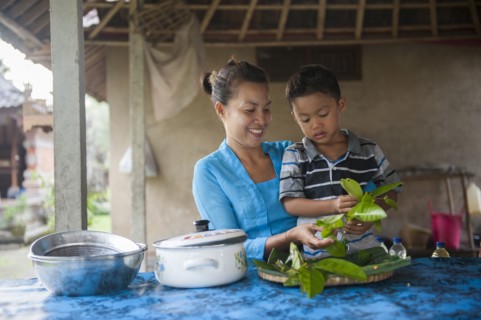 Asian mother and son cooking in outdoor kitchen