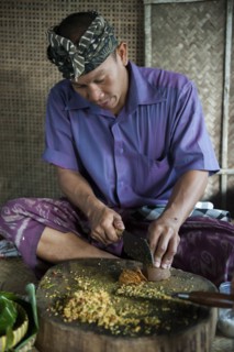 Asian man grinding spices on cutting board