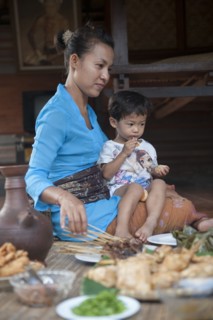 Asian mother and son eating on woven mat
