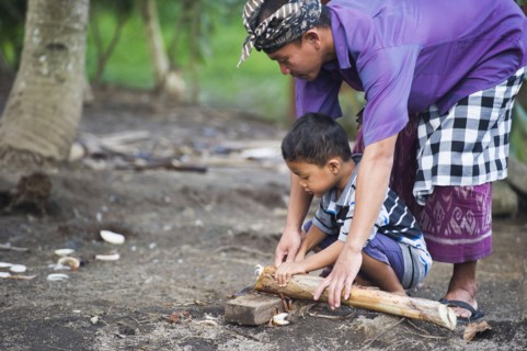 Asian father teaching son traditional wood carving