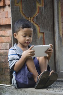Asian boy using cell phone on front step