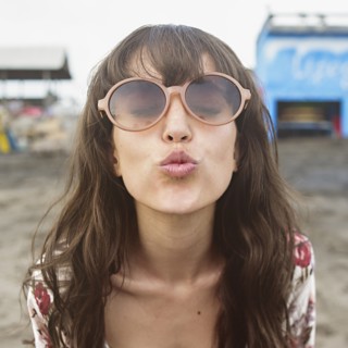 Caucasian woman in sunglasses puckering to kiss at beach