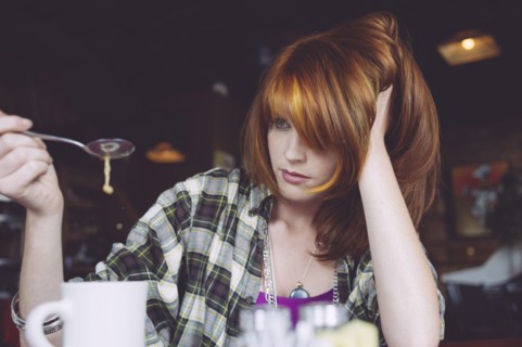 Caucasian woman playing with coffee in cafe
