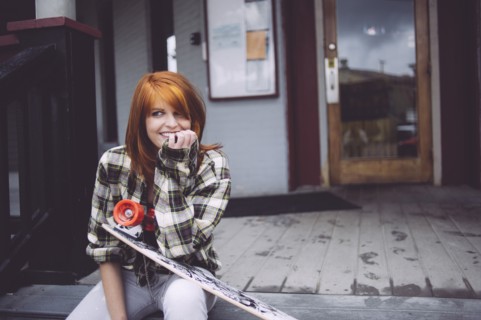 Caucasian woman holding skateboard on patio