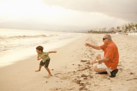 Grandfather and grandson playing on beach together