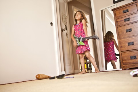 Mixed race girl playing guitar in bedroom