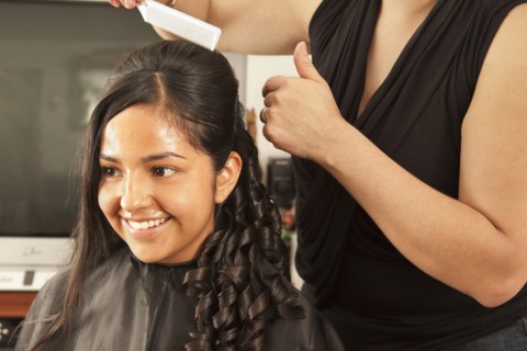 Hispanic woman having hair styled in salon