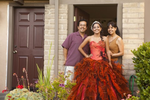 Hispanic girl dressed for quinceanera standing with parents