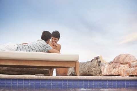 Hispanic couple relaxing at poolside